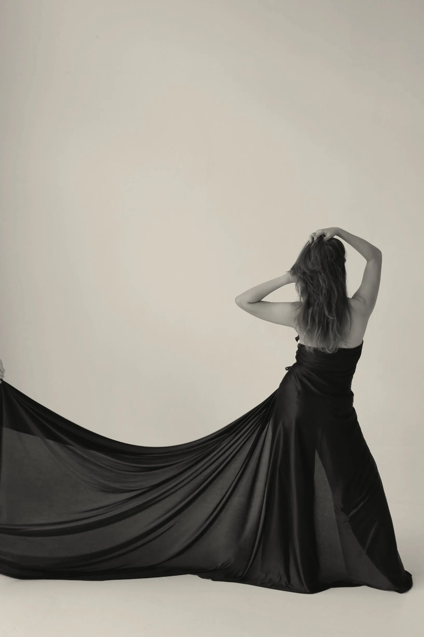 A woman in a long dark dress, seen from behind, in black and white
