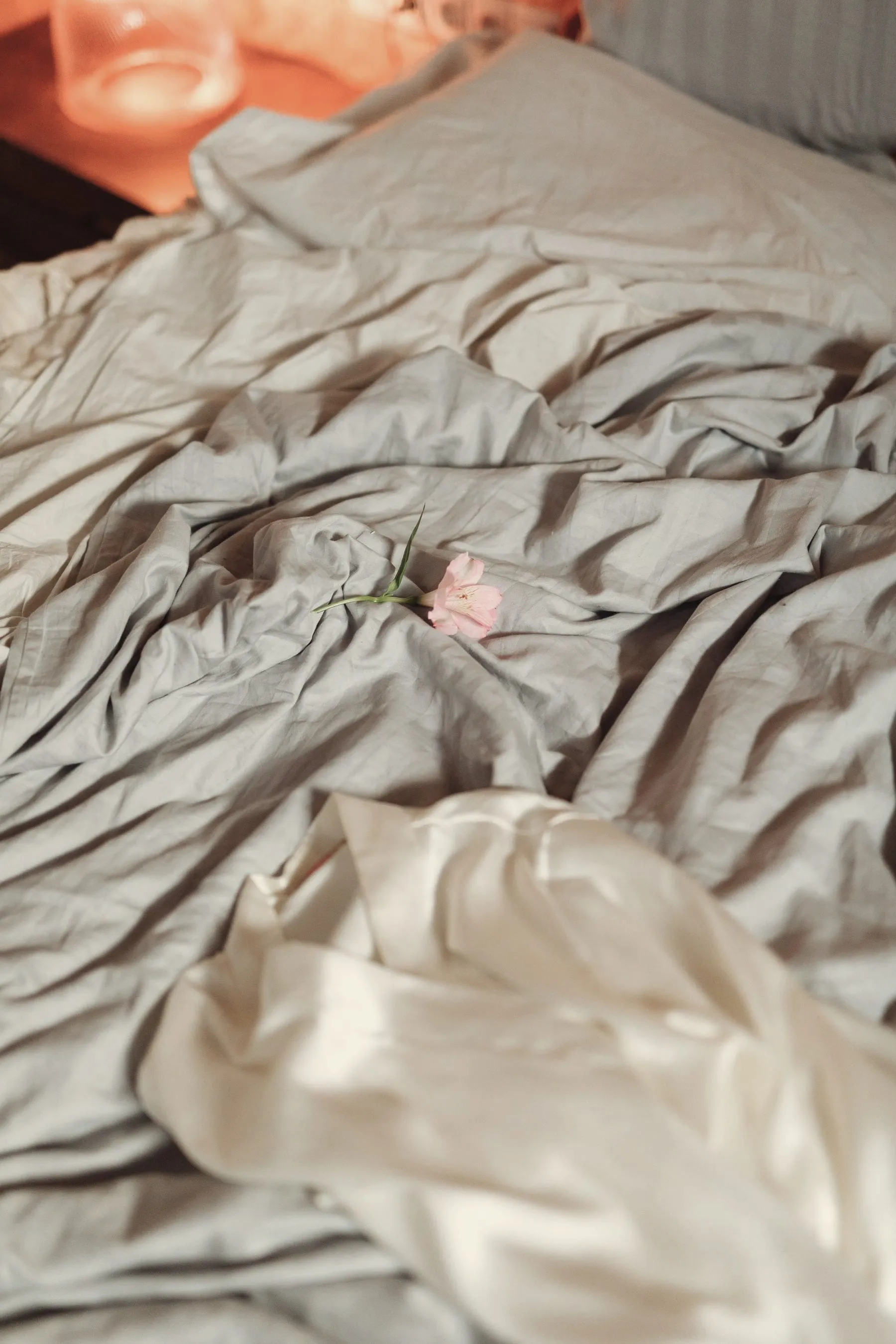 A pink flower on crumpled sheets